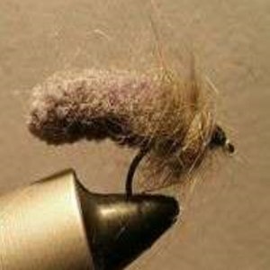 May include: A brown and tan fly fishing lure with a fuzzy body and a hook.