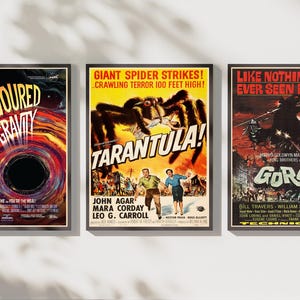 May include: Three framed vintage-style movie posters. The left poster features a black hole with the text Devoured by Gravity. The center poster shows a giant spider with the text Tarantula. The right poster depicts a monster with the text Gorgo.
