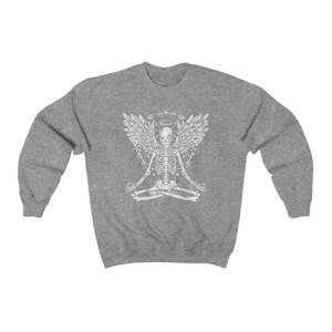 May include: A grey sweatshirt with a white graphic of a skeleton meditating with angel wings and a halo. The skeleton is in a lotus position, with detailed wings and design elements. A casual, comfortable garment.