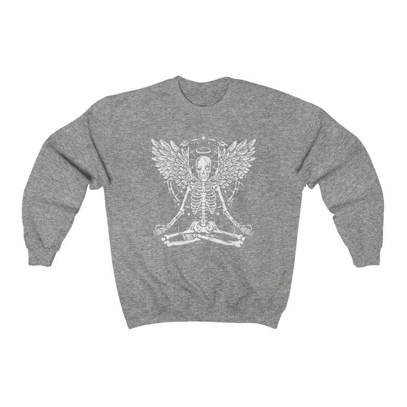 May include: A grey sweatshirt with a white graphic of a skeleton meditating with angel wings and a halo. The skeleton is in a lotus position, with detailed wings and design elements. A casual, comfortable garment.