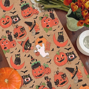 May include: A tan table runner featuring a repeating Halloween pattern of orange jack-o'-lanterns, black cats, green-eyed owls on orange crescent moons, white ghosts, and witches in hats, all illustrated in a vintage, colorful graphic style.