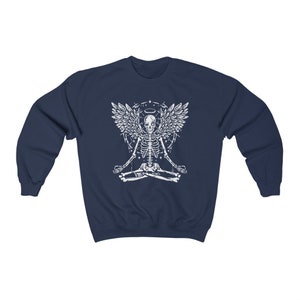 May include: Navy blue sweatshirt with a white graphic of a skeleton angel in a yoga pose. The design includes a halo and geometric shapes. The sweatshirt is made of a soft, comfortable material.