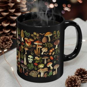 May include: Black ceramic mug with a vintage illustration of various mushrooms and foliage. The mug is filled with coffee and steam is rising from the top.