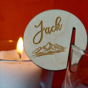 K&ouml;nnte beinhalten: Ein Holz-Namensschild mit dem Namen "Jack" eingraviert. Das Schild hat au&szlig;erdem ein lasergeschnittenes Design einer Bergkette.