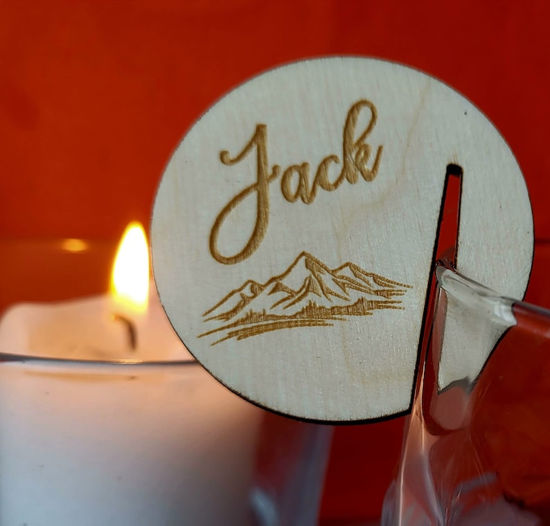 K&ouml;nnte beinhalten: Ein Holz-Namensschild mit dem Namen "Jack" eingraviert. Das Schild hat au&szlig;erdem ein lasergeschnittenes Design einer Bergkette.