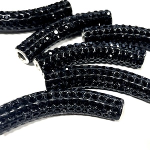 May include: Five black curved beads with a sparkly finish. The beads are made of rhinestones and have a silver metal core.