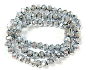 May include: A strand of silver faceted glass beads. The beads are round and have a shiny, metallic finish.