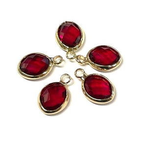 May include: Five red glass oval-shaped charms with gold-tone metal settings and jump rings. The charms are perfect for adding a touch of sparkle to jewelry projects.