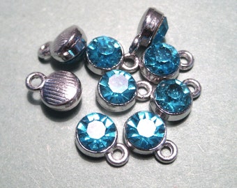 May include: A group of eight turquoise blue rhinestone charms with silver settings. Each charm has a loop for attaching to a necklace, bracelet, or other jewelry.