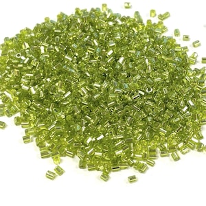 Könnte beinhalten: Ein großer Haufen kleiner, grüner Glasperlen mit einem metallischen Schimmer.