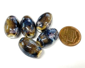 May include: Five ceramic beads with a brown, blue and white marbled glaze. The beads are oval shaped and have a hole through the centre. The beads are about the size of a UK penny.