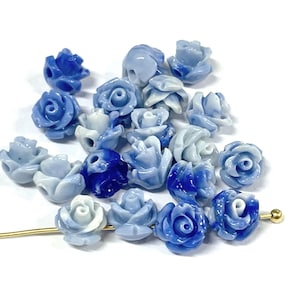 May include: A collection of blue and white ceramic rose flower beads. The beads are ombre, with the color transitioning from white to blue.
