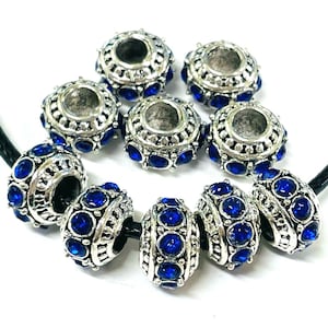 May include: A set of silver-toned beads with blue rhinestone accents. The beads have a round shape and a hole in the center for threading.