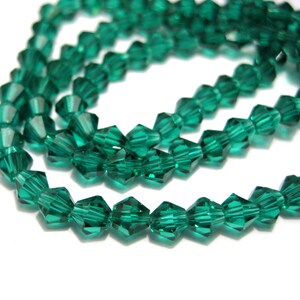 May include: A strand of emerald green faceted glass beads. The beads are small and have a diamond-like shape.