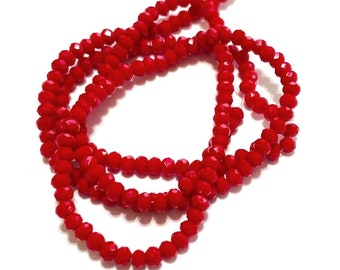 May include: A strand of red faceted glass beads. The beads are small and uniform in size. The strand is coiled and ready for use in jewelry making.