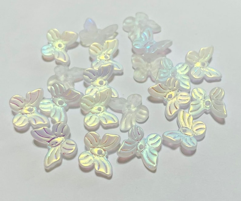 K&ouml;nnte beinhalten: Eine Sammlung von irisierenden wei&szlig;en Perlen in Schmetterlingsform. Die Perlen haben eine Perlmutt-Oberfl&auml;che und sind perfekt zum Basteln von Schmuck oder zum Hinzuf&uuml;gen eines Schimmers zu jedem Projekt.