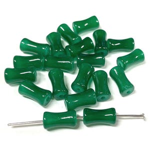 May include: A collection of green glass beads with a distinctive hourglass shape. The beads are strung on a silver-colored wire, showcasing their glossy finish. The beads are approximately 0.75 inches long, perfect for jewelry making.