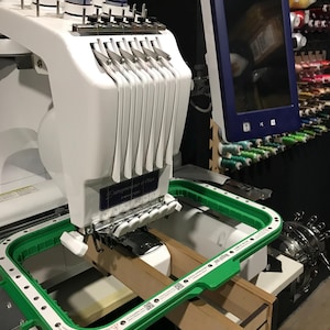 May include: A white embroidery machine with a green hoop and a blue screen that says "brother".