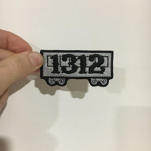 Może przedstawiać: Naszywka haftowana w kolorze czarnym i białym w kształcie wagonu kolejowego z numerem "1312" na niej.