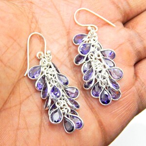 May include: A pair of silver dangle earrings with multiple teardrop-shaped amethyst gemstones. The earrings are made of sterling silver and feature a cascading design.