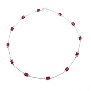 May include: A silver necklace with rectangular, deep red gemstones. The gemstones are set along a fine chain, creating a minimalist design. The necklace is displayed against a white background. The chain is approximately 40 cm in length.