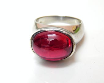 Könnte beinhalten: Ein silberner Ring mit einem großen, ovalen, roten Edelstein.
