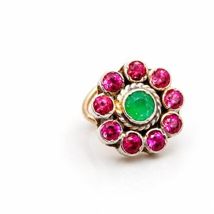 Puede incluir: Un anillo que presenta una piedra preciosa verde redonda central rodeada por un halo de nueve pequeñas piedras preciosas rosas redondas. El engaste está hecho de una combinación de metal amarillo y blanco, con una textura de cuerda trenzada.