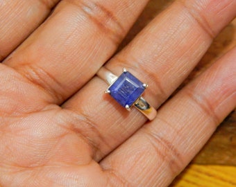 May include: A silver ring with a square blue gemstone.