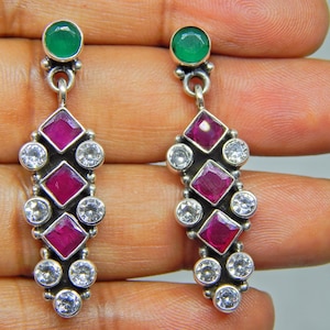May include: Silver dangle earrings with a green gemstone at the top and a cascade of pink and white gemstones.
