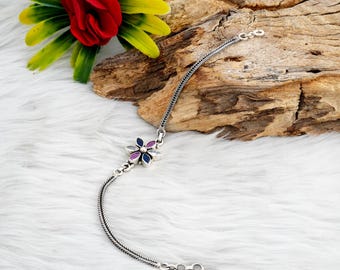 May include: A silver chain bracelet with a flower charm. The flower has five petals with blue, pink, and white enamel.