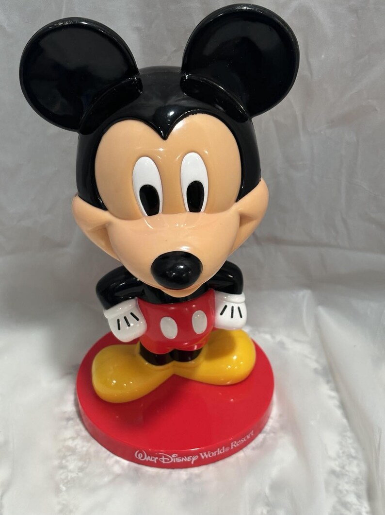 K&ouml;nnte beinhalten: Mickey Mouse-Figur mit schwarzem Kopf und Ohren, hellbraunem Gesicht und roter Basis. Die Figur hat wei&szlig;e Handschuhe, rote Shorts mit wei&szlig;en Kn&ouml;pfen und gelbe Schuhe. Auf der Basis steht "Walt Disney World Resort."