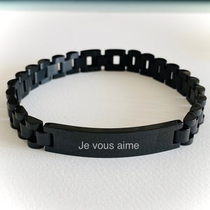 May include: A black stainless steel bracelet with a rectangular tag that reads "Je vous aime".