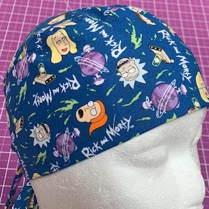 May include: A blue surgical scrub cap featuring cartoon characters and the words "Rick and Morty" in white. The cap has a tie closure and is made of a patterned fabric with images of characters, planets, and other elements from the animated series.
