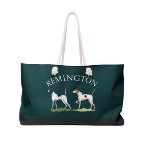 May include: A large tote bag with a dark teal background and a black bottom. The bag features two dog illustrations and the word "REMINGTON" in white. The bag has white rope handles.