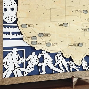 May include: A wooden map of the United States with hockey arenas marked with puck-shaped icons. The map is framed in wood and has a blue background with hockey players cut out of the wood. The map is on a wooden stand.