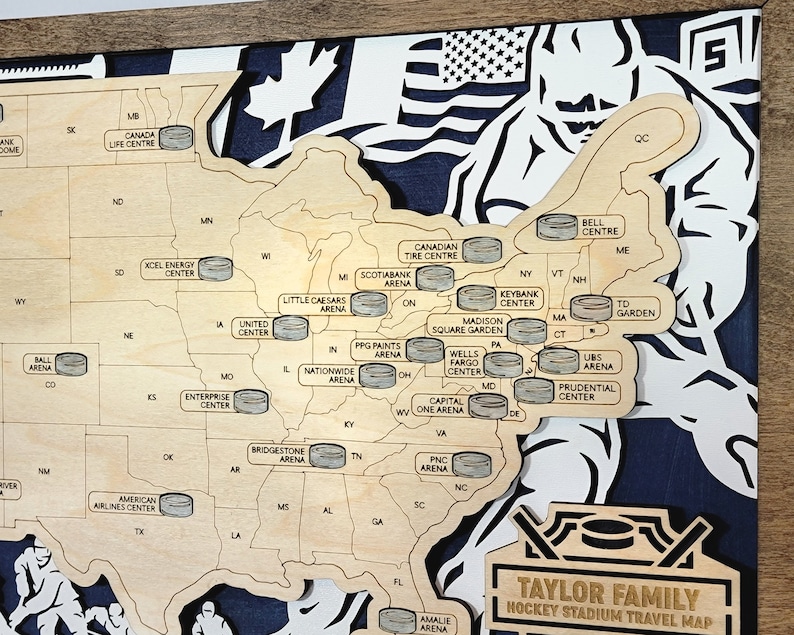 May include: A wooden map of the United States with hockey pucks marking the locations of different hockey arenas. The map is labeled "Taylor Family Hockey Stadium Travel Map".