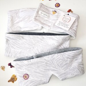 May include: White eye mask with a gray fleece lining and a white and gray zebra print. The eye mask is handmade and has a label that reads "Zero Waste Textile Products, Vienna, handcrafted print, Color: Zebra Grey Print, &euro; 16".