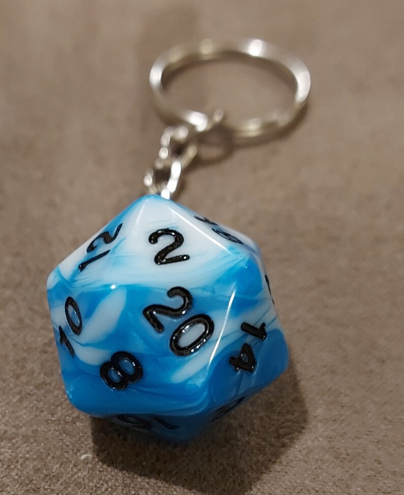 May include: A blue and white marbled 20-sided die with black numbers on each side. The die is attached to a silver keychain.