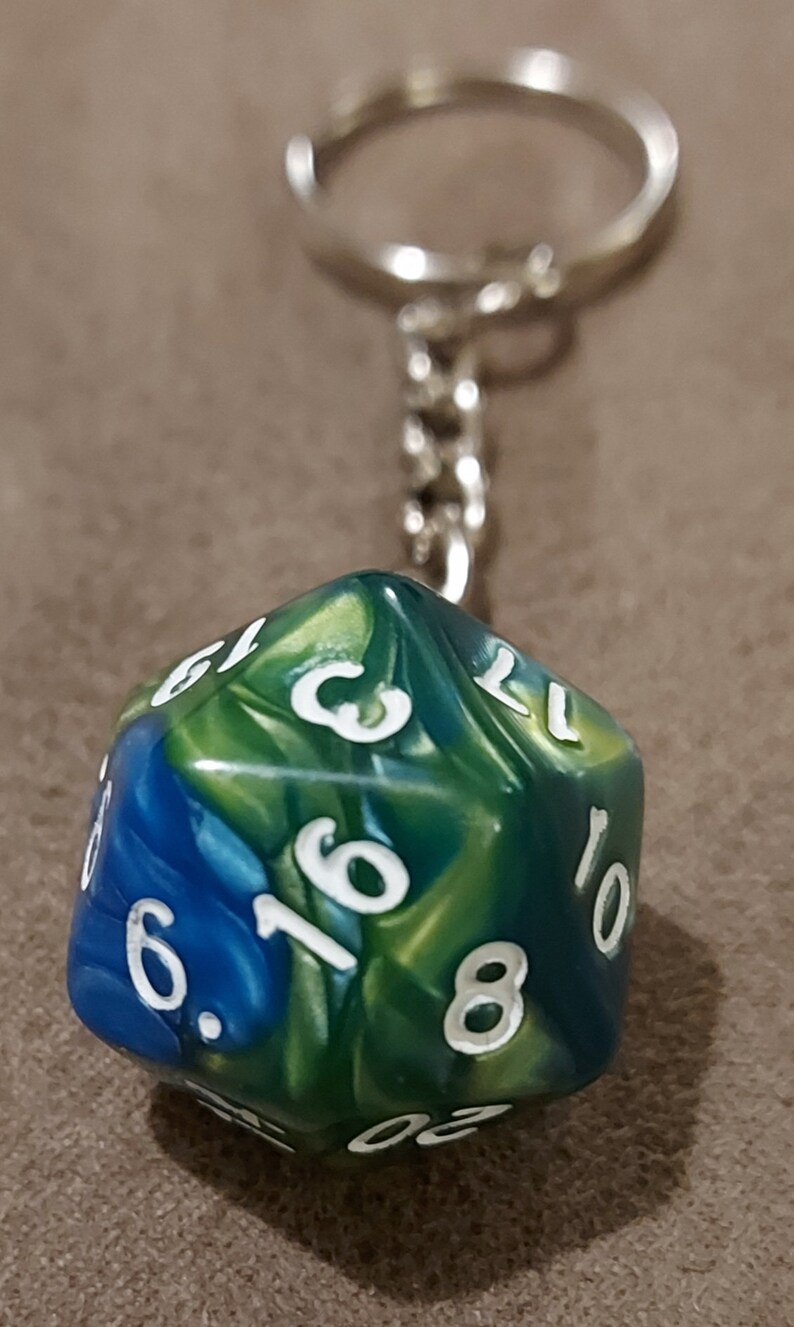 May include: A green, blue, and gold iridescent keychain with a 10-sided die. The die has white numbers on each side.