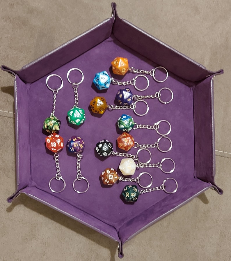 May include: A purple velvet dice tray with 10 different colored dice on keychains. The dice are all different colors and have different numbers on them. The keychains are all silver.