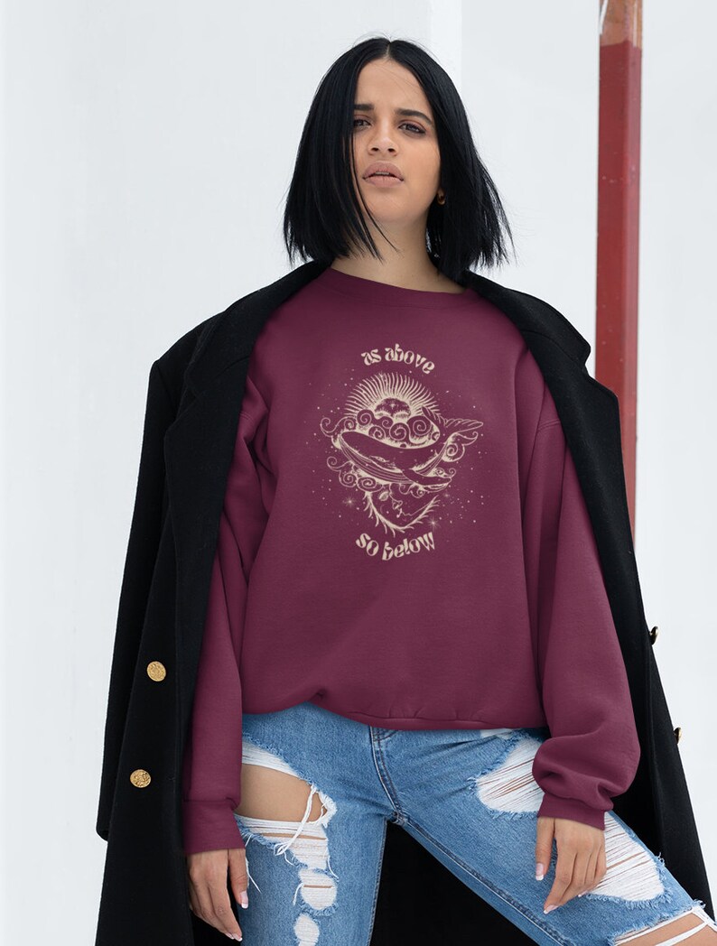 May include: A maroon sweatshirt with a graphic design of a sun, moon, and whale with the text "as above so below".