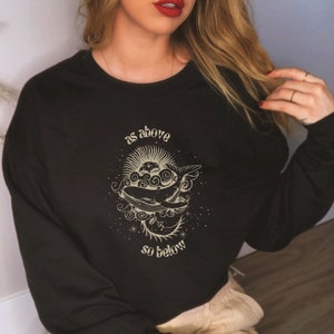May include: Black sweatshirt with a gold graphic of a whale and the text "as above so below".