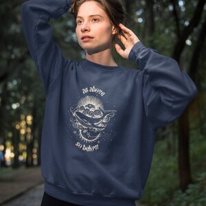 May include: A navy blue sweatshirt with a white graphic of a whale swimming in a starry sky. The graphic includes the text "as above so below".