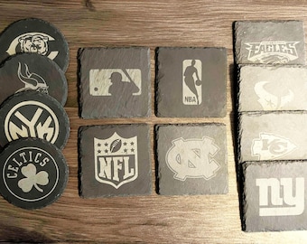 May include: A set of 10 black slate coasters with various sports team logos, including the NFL, NBA, MLB, and NHL. The logos are engraved in white.