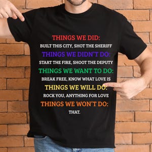 K&ouml;nnte beinhalten: Schwarzes T-Shirt mit farbigem Text, der Dinge auflistet, die getan wurden, nicht getan wurden, gew&uuml;nscht werden und getan werden. Der Text enth&auml;lt S&auml;tze wie "Built this city".