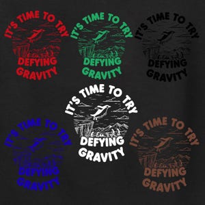 Könnte beinhalten: Dunkler Hintergrund mit sechs kreisförmigen Designs, die einen Pinguin zeigen, der von einer Klippe springt. Jedes Design enthält den Text "IT'S TIME TO TRY" und "DEFYING GRAVITY" in verschiedenen Farben: Rot, Grün, Schwarz, Blau, Weiß und Braun.