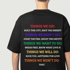 K&ouml;nnte beinhalten: Schwarzes T-Shirt mit mehrfarbigem Text auf der R&uuml;ckseite. Der Text ist in Abschnitte unterteilt: &bdquo;Dinge, die wir getan haben&ldquo;, &bdquo;Dinge, die wir nicht getan haben&ldquo;, &bdquo;Dinge, die wir tun wollen&ldquo;, &bdquo;Dinge, die wir tun werden&ldquo; und &bdquo;Dinge, die wir nicht tun werden&ldquo;.