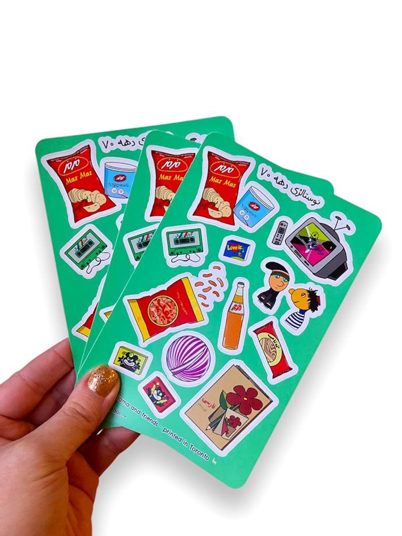 sticker sheets featuring nostalgic persian elements from the 90s, held in hand, against a white background