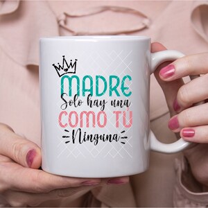 May include: White ceramic mug with a teal green and pink design that says "Madre Solo hay una como tu Ninguna".