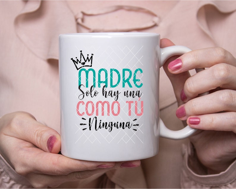 May include: White ceramic mug with a teal green and pink design that says "Madre Solo hay una como tu Ninguna".